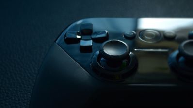 Controlador de juegos con botones y joysticks en superficie oscura.