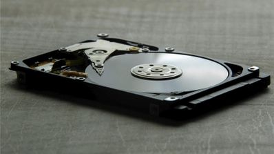 Plato de un disco duro magnético reflejando código binario, ilustrando el concepto de recuperación de datos a nivel físico
