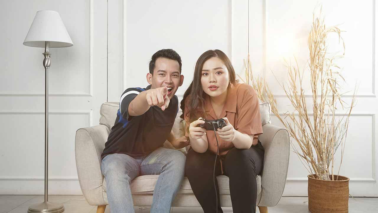 Hombre y mujer sentados en un sofá jugando con una consola