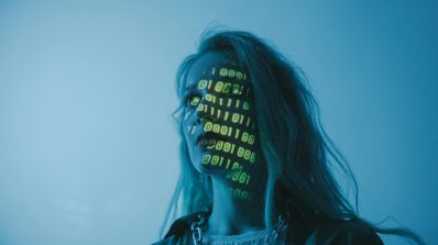 Representación conceptual de la ciberseguridad, mostrando un rostro de mujer fusionado con código binario y caracteres alfanuméricos