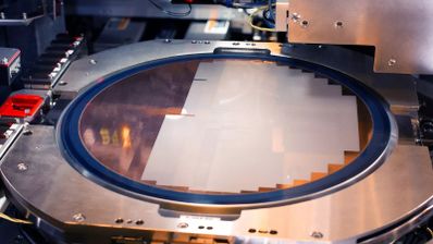 Brazo robótico manipulando una oblea de silicio en una sala blanca de la fundición de Intel en Ocotillo, Arizona, durante el proceso de litografía para el nodo 18A.