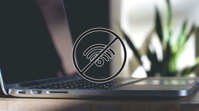 Símbolo de Wi-Fi tachado en sobre un fondo con un portátil, representando problemas de conexión inalámbrica.