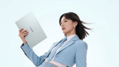 Mujer con traje azul claro sosteniendo con una mano un ordenador portátil Lenovo Xiaoxin Air 14 de color plata sobre fondo blanco.