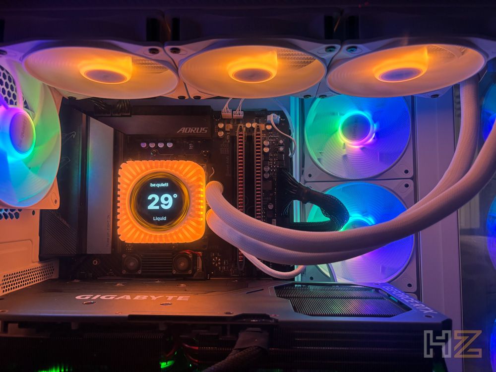 Interior de un ordenador con refrigeración líquida be quiet! Light Loop, bloque con pantalla LCD que muestra 29 grados y ventiladores con iluminación ARGB naranja y multicolor.
