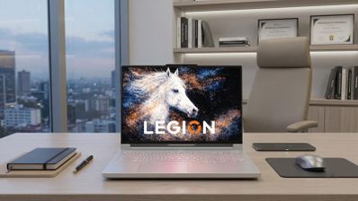 Portátil Lenovo Legion R9000P de color blanco sobre un escritorio de oficina con vistas a la ciudad al atardecer.