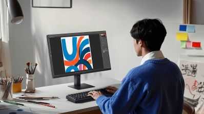 Persona trabajando en diseño gráfico con el monitor Xiaomi A27I en un escritorio organizado.