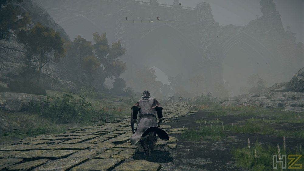 Personaje de Elden Ring caminando por un sendero empedrado hacia una fortaleza rodeada de niebla.