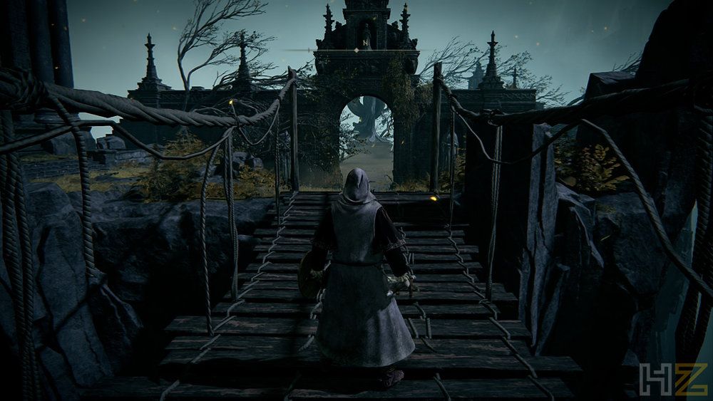 Personaje de Elden Ring cruzando un puente de madera hacia una estructura gótica bajo un cielo nublado.