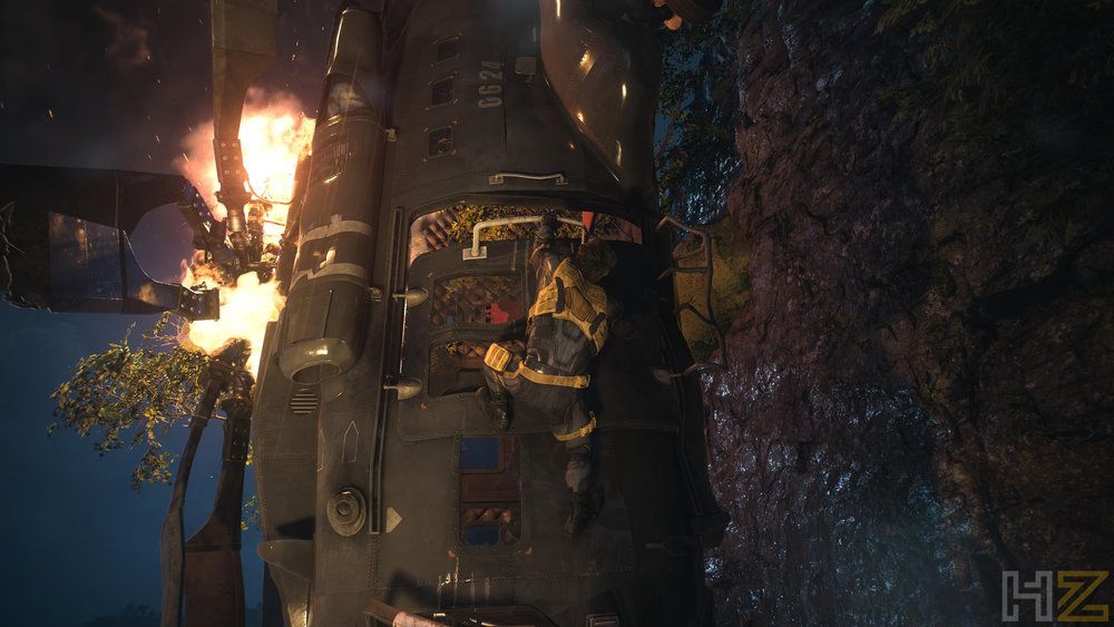 Lobezno frente a un helicóptero accidentado en llamas durante una escena nocturna.
