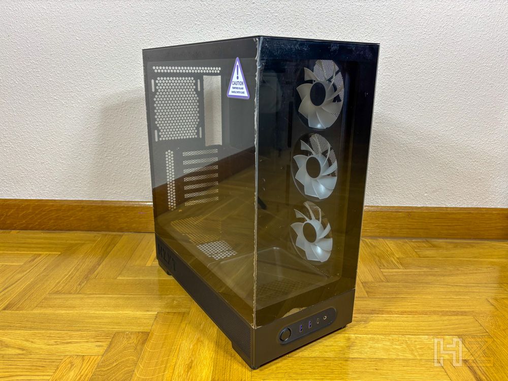 Chasis de PC NZXT S5 RGB con paneles frontales y laterales de cristal templado en perspectiva diagonal sobre suelo de madera.