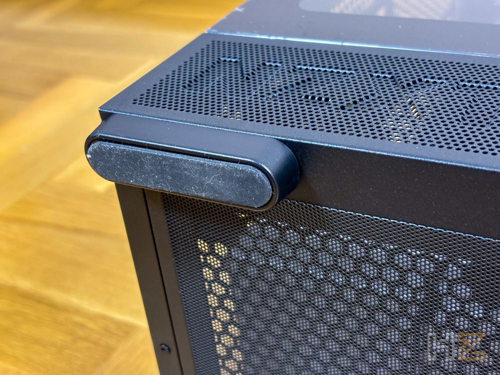 Primer plano de la base de la caja de PC NZXT S5 RGB mostrando una de sus patas antideslizantes sobre un suelo de madera.