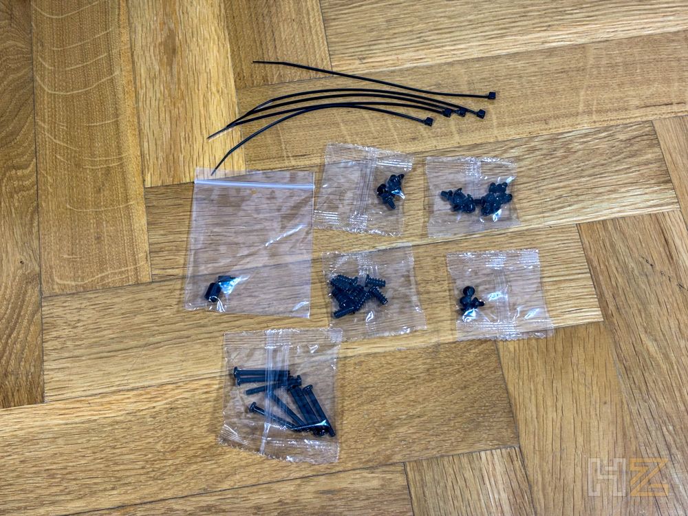 Conjunto de tornillería y bridas para montaje de chasis de PC sobre suelo de madera.