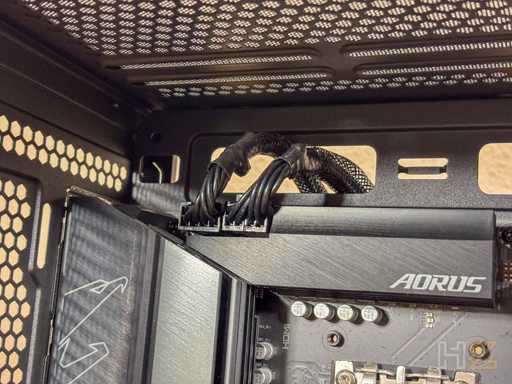 Detalle de los cables de alimentación de la CPU conectados a una placa base Aorus dentro de una caja NZXT S5 RGB.