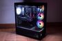 Ordenador de sobremesa NZXT S5 RGB con paneles de cristal templado y ventiladores iluminados funcionando en una habitación con poca luz.
