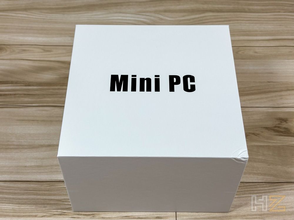 Caja blanca con el texto Mini PC sobre una mesa de madera.