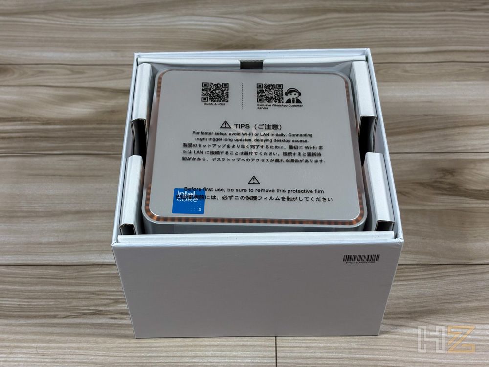 Primer plano del Mini PC NiPoGi P2 dentro de su caja blanca protectora sobre una mesa de madera.