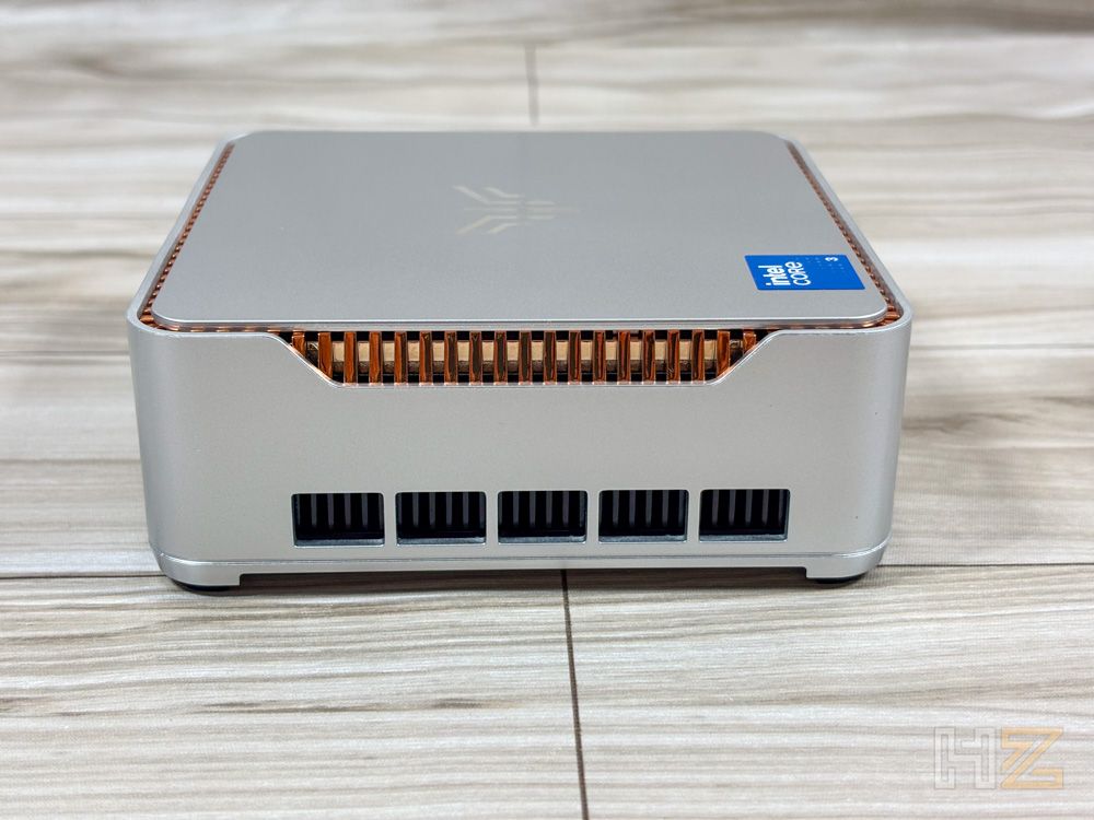 Vista lateral del mini PC NiPoGi P2 que muestra las ranuras de ventilación inferiores y la rejilla superior en color cobre.