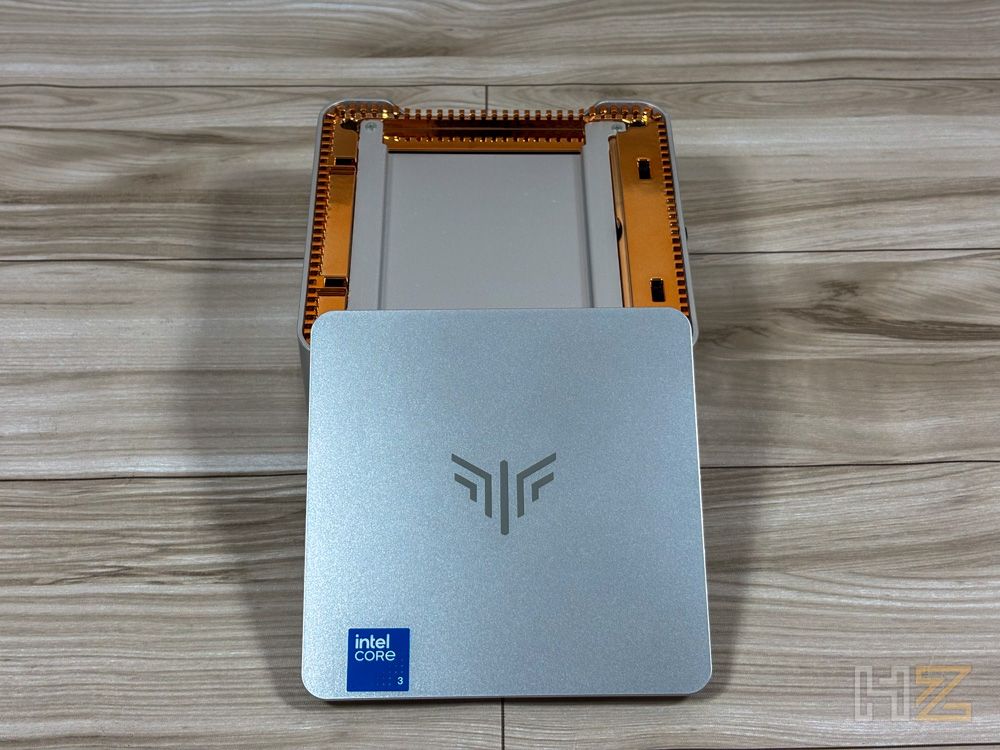 Vista superior del mini PC NiPoGi P2 abierto sobre una mesa de madera, mostrando la tapa metálica con el logo de la marca y el interior del chasis.