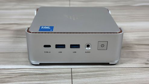 Panel frontal del mini PC NiPoGi P2 con puertos USB-C, USB-A y jack de audio sobre una superficie de madera.