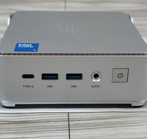 Panel frontal del mini PC NiPoGi P2 con puertos USB-C, USB-A y jack de audio sobre una superficie de madera.