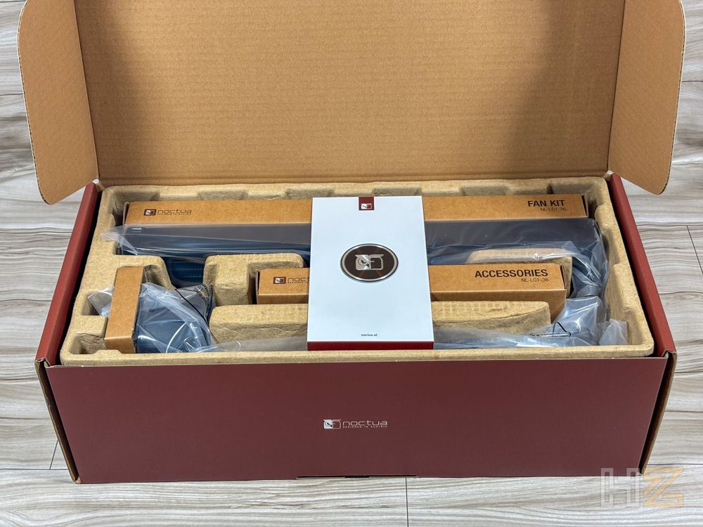 Contenido del paquete del Noctua NL-LC1 con accesorios y manual organizados en compartimentos de cartón.