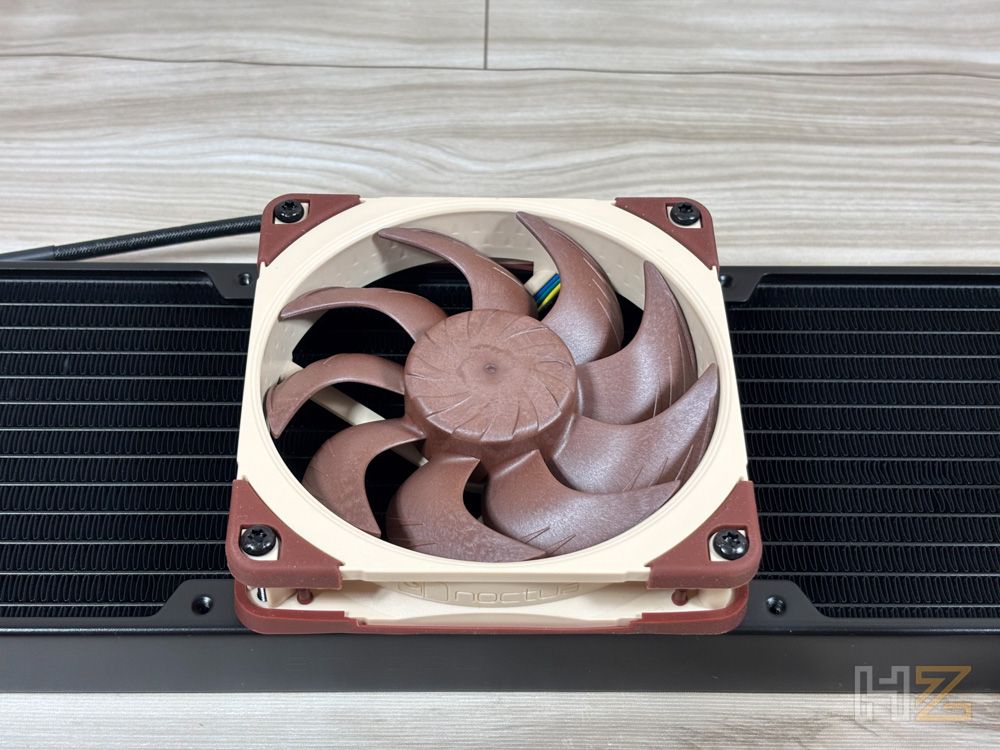Primer plano de un ventilador Noctua con aspas marrones instalado sobre un radiador de refrigeración líquida negro.