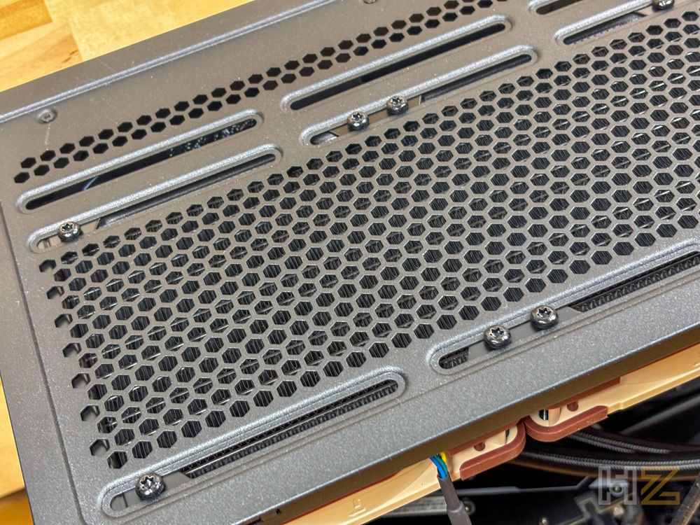 Primer plano de la rejilla superior de una caja de PC con tornillos de montaje instalados.