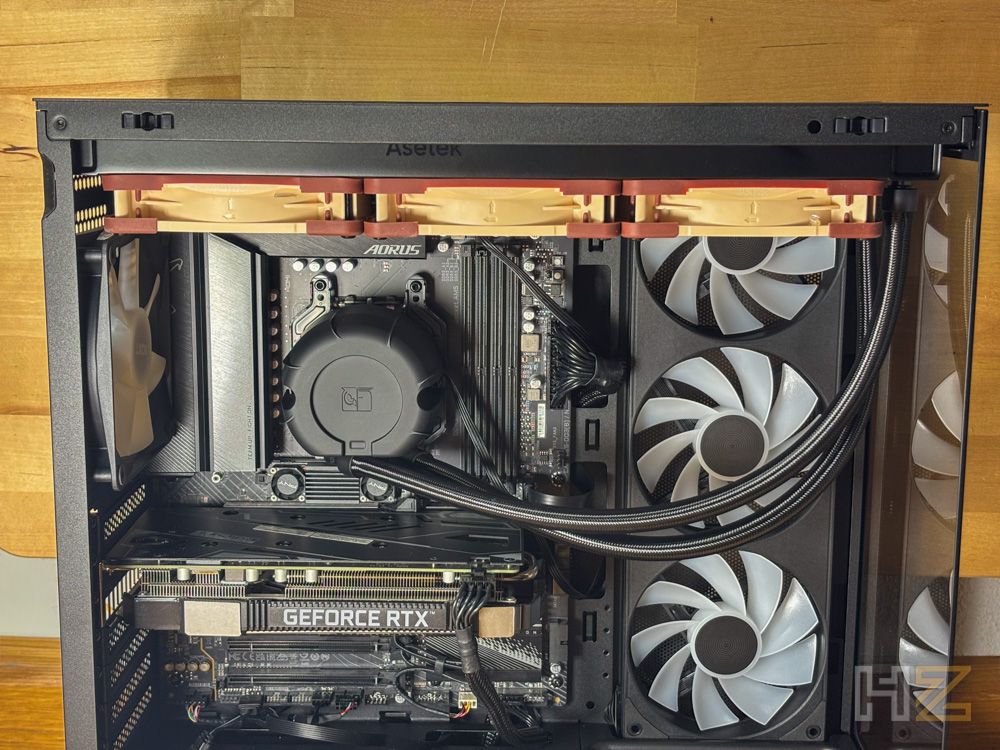 Interior de una caja de PC con placa base Aorus, tarjeta gráfica GeForce RTX y sistema de refrigeración con ventiladores Noctua instalados en la parte superior.