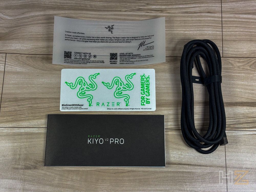 Accesorios incluidos con la cámara Razer Kiyo V2 Pro sobre una mesa de madera.