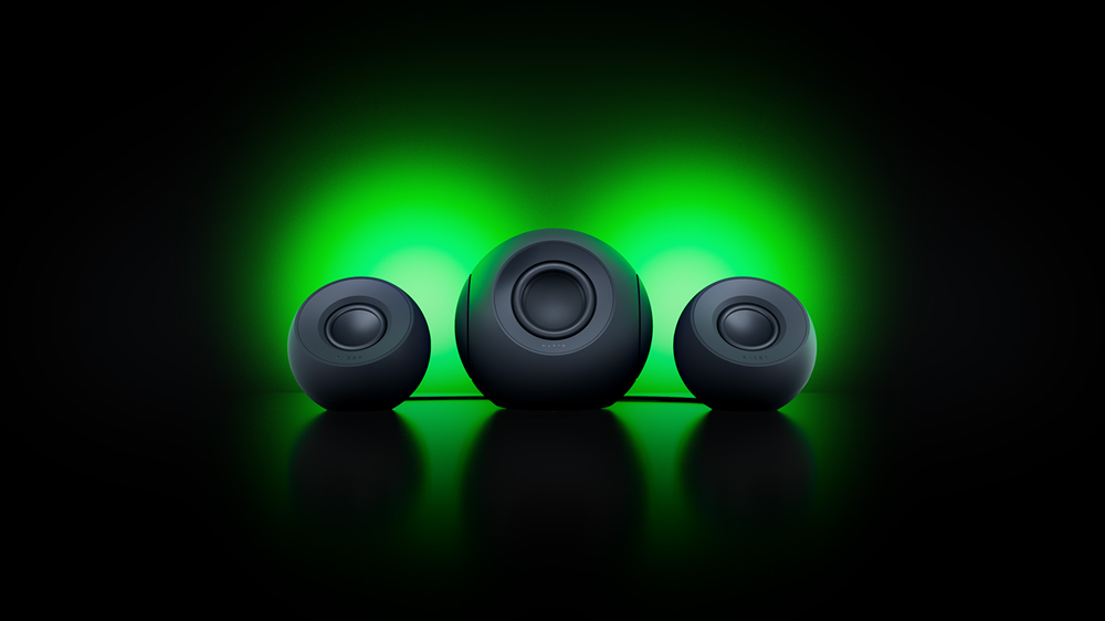 Tres altavoces Mako de forma esférica alineados sobre una superficie oscura con retroiluminación ambiental verde.