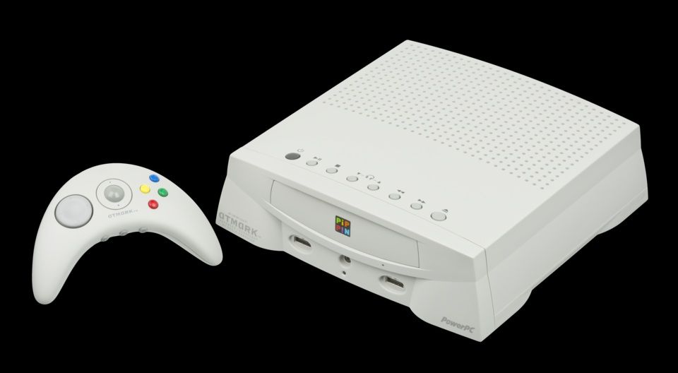 Videoconsola Apple Pippin de color blanco junto a su mando inalámbrico con trackball central.