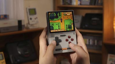 Primer plano de una consola portátil KONKR Pocket Block en las manos de un usuario ejecutando un juego de estética retro.