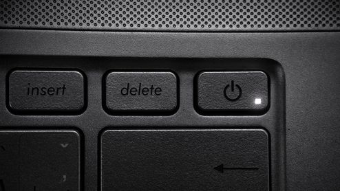 Detalle de la tecla Delete en el teclado de un ordenador portátil junto al botón de encendido.