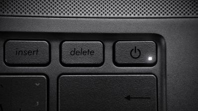Detalle de la tecla Delete en el teclado de un ordenador portátil junto al botón de encendido.