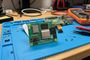 Placa Raspberry Pi Compute Module 5 sobre una alfombra de trabajo azul en un taller de electrónica.