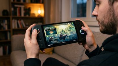 Primer plano de una persona sosteniendo una consola portátil con SteamOS mostrando el juego Elden Ring en pantalla.