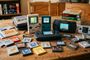 Colección de consolas portátiles clásicas y cartuchos de videojuegos sobre una mesa de madera.