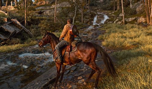 Personaje a caballo cruzando un riachuelo en un bosque de montaña durante el atardecer en un videojuego.
