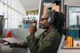 Hombre con rastas trabajando en una oficina luminosa con los auriculares Logitech Zone Vibe Pro puestos mientras mira el monitor.