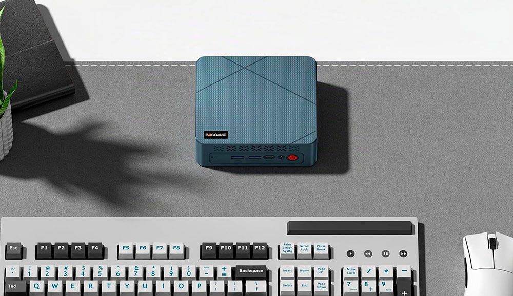 Vista superior del mini PC BOSGAME E2 Air en color azul sobre un escritorio con teclado y ratón.