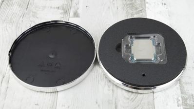 Procesador Intel en su embalaje protector circular abierto sobre una mesa de madera blanca.