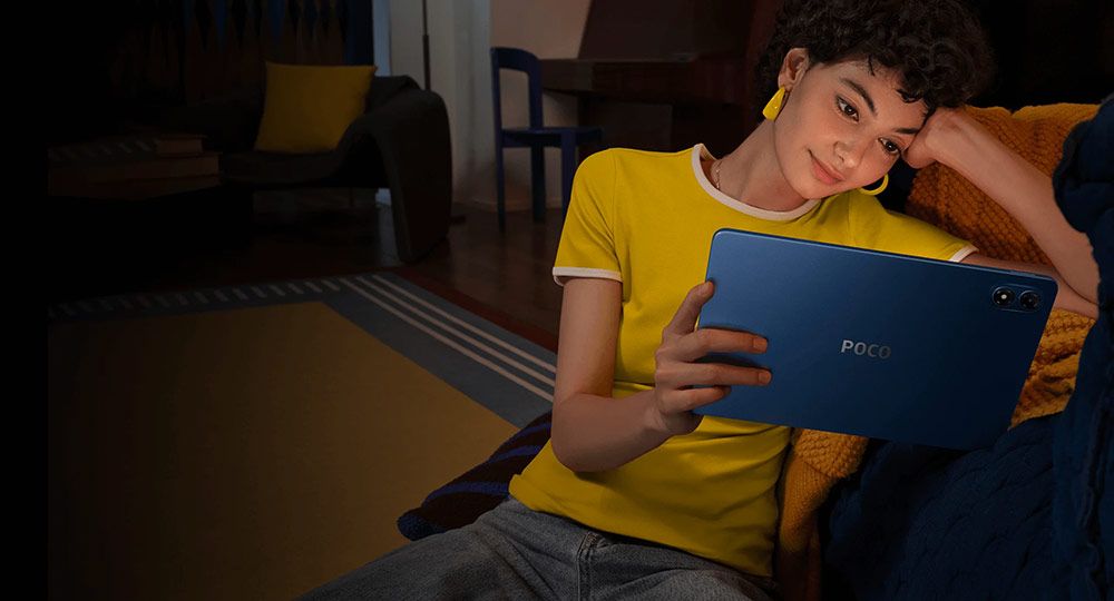 Persona sentada en un sofá sosteniendo la tablet POCO Pad M1 de color azul en un entorno doméstico.