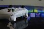 Mando inalámbrico de Xbox de color blanco sobre una mesa con una interfaz de juegos de Smart TV desenfocada al fondo.
