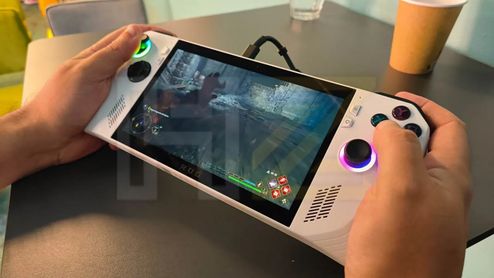 Primer plano de una consola portátil Asus ROG Ally blanca sostenida con ambas manos sobre una mesa.