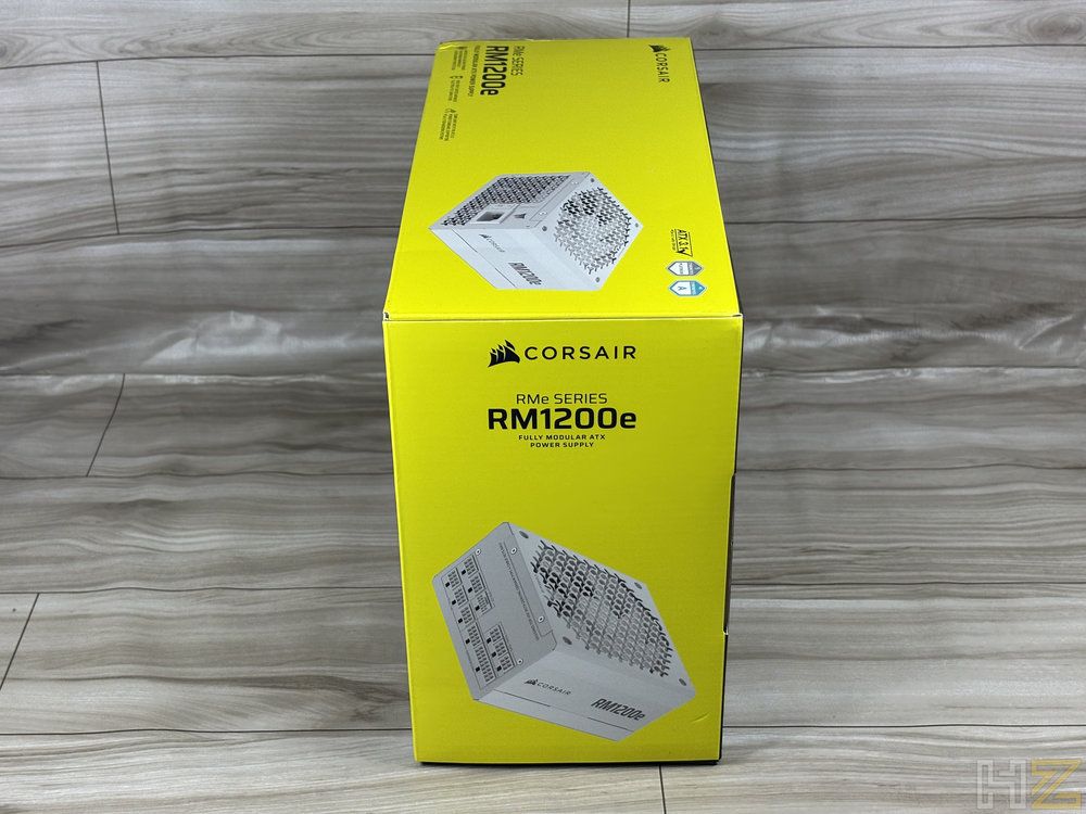Embalaje comercial amarillo de la fuente de alimentación Corsair RM1200e visto desde un lateral.