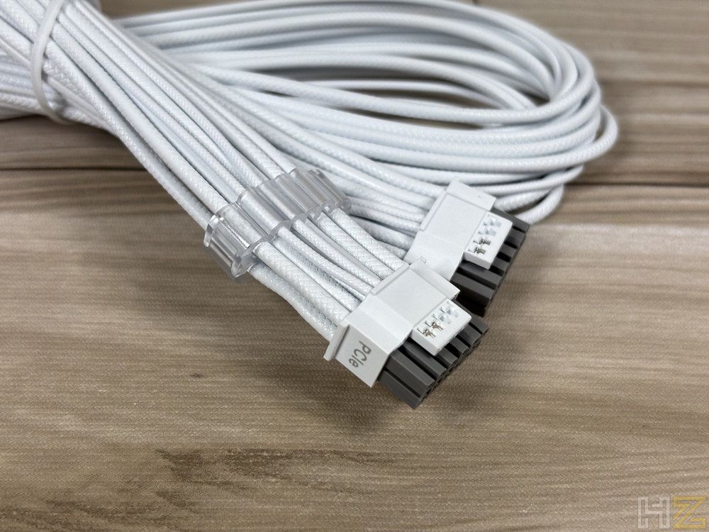 Primer plano de los conectores PCIe blancos de la fuente de alimentación Corsair RM1200e sobre una superficie de madera.