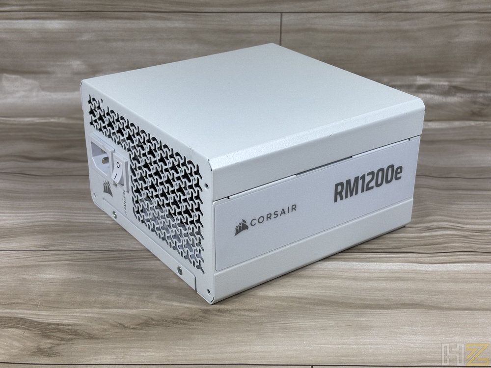 Fuente de alimentación Corsair RM1200e en color blanco sobre una superficie de madera.