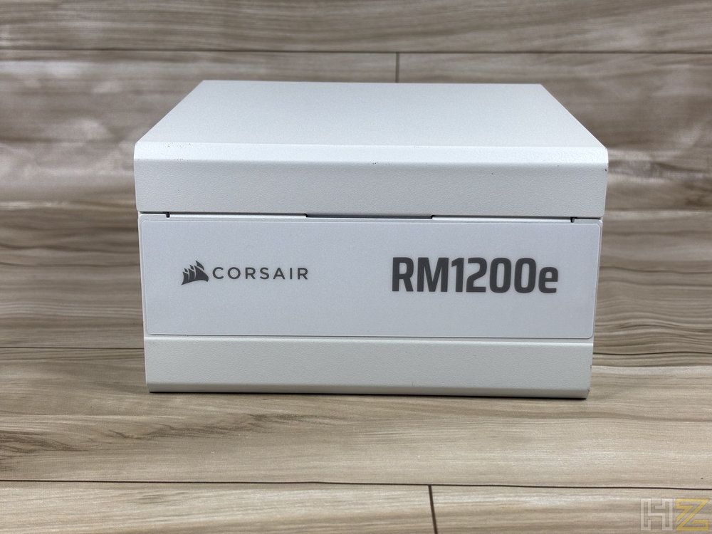 Caja blanca de la fuente de alimentación Corsair RM1200e sobre una superficie de madera.
