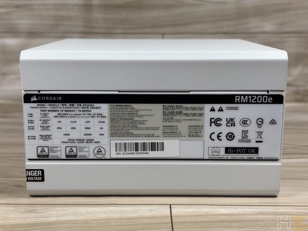 Etiqueta de especificaciones técnicas y certificaciones en el lateral de una fuente de alimentación blanca Corsair RM1200e.