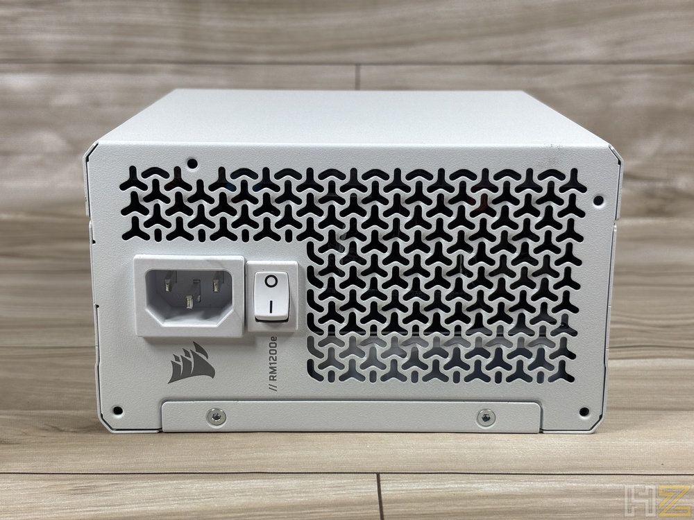 Parte trasera de la fuente de alimentación blanca Corsair RM1200e con conector de corriente y rejilla de ventilación.